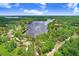 Aerial view of a lakeside property, highlighted with red lines, surrounded by lush greenery and calm waters at 8903 Donna Lu Dr, Odessa, FL 33556