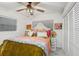 Bright bedroom with wood-look floors, ceiling fan, closet and colorful bedding creates a cheerful and inviting space at 8903 Donna Lu Dr, Odessa, FL 33556