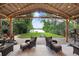Relaxing outdoor seating area under a tiki hut with a view of the backyard and lake at 8903 Donna Lu Dr, Odessa, FL 33556