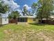 Spacious backyard featuring a screened lanai, wood fence, large storage shed, and mature trees at 932 W Wheeler Rd, Brandon, FL 33510