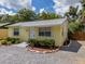 Attractive yellow home with neat landscaping, a gravel driveway, and a welcoming front door at 932 W Wheeler Rd, Brandon, FL 33510