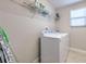Well-lit laundry room with white washer and dryer, wire rack, and window with blinds at 10081 Sage Creek Dr, Sun City Center, FL 33573