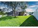 Spacious backyard featuring a well-manicured lawn, screened-in pool enclosure, and mature trees, offering privacy at 10513 Palm Cove Ave, Tampa, FL 33647