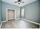 Light-filled bedroom boasts gray walls, wood floors, ceiling fan, and open closet at 10513 Palm Cove Ave, Tampa, FL 33647