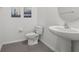 Bathroom featuring pedestal sink, toilet, and grey tile flooring at 10823 Trailing Vine Dr, Tampa, FL 33610