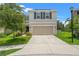 Charming two-story home featuring a well-maintained lawn and a two-car garage on a sunny day at 10823 Trailing Vine Dr, Tampa, FL 33610