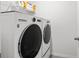 Laundry room featuring a front loading washer and dryer with white shelving at 10823 Trailing Vine Dr, Tampa, FL 33610