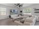 Bright living room featuring white leather sectional, modern fan, and large windows at 10823 Trailing Vine Dr, Tampa, FL 33610