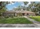 Charming single-story home with a well-manicured lawn, mature trees, and solar panels on the roof at 10902 Bent Tree Pl, Tampa, FL 33618