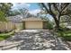 Two-car garage with brick accents, long driveway, and mature landscaping at 10902 Bent Tree Pl, Tampa, FL 33618