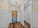 Stylish entryway with decorative wallpaper, white wainscoting, wood floors, and a pendant light fixture at 12492 Eastpointe Dr, Dade City, FL 33525