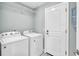 Well-lit laundry room with washer, dryer, white door, and shelving at 1901 Paddock Dr, Plant City, FL 33566