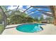 Sparkling pool with blue tile in a screened enclosure surrounded by green trees and sky at 1901 Paddock Dr, Plant City, FL 33566