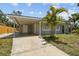 View of the home's carport and driveway, accentuated by a vibrant palm tree and modern gray paint at 1905 E Broad St, Tampa, FL 33610