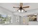 Living room featuring a decorative ceiling fan, white walls, and open concept to the kitchen at 1905 E Broad St, Tampa, FL 33610