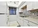 Well-lit kitchen featuring white cabinets, stylish backsplash, and modern appliances at 2003 Greenbriar Blvd # 8, Clearwater, FL 33763
