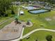 An aerial view showcasing the community playground, pool and tennis courts surrounded by lush greenery and walking paths at 20108 Stone Pine Cir, Lutz, FL 33558