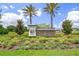 The Reserve at Long Lake Ranch community sign featuring lush landscaping and mature palm trees under a bright blue, cloud-filled sky at 20108 Stone Pine Cir, Lutz, FL 33558