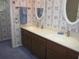 Well-lit bathroom featuring a double vanity, decorative wallpaper, and elegant fixtures at 2143 Wrens Way, Clearwater, FL 33764