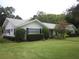 Traditional single-story home featuring a well-manicured lawn, decorative bushes, and black shutters at 2143 Wrens Way, Clearwater, FL 33764