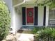 Front door with brick facade, black shutters, red door, lantern and attractive landscaping at 2143 Wrens Way, Clearwater, FL 33764