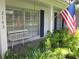 Inviting front porch showcasing a comfortable bench, decorative ferns, and an American flag at 2143 Wrens Way, Clearwater, FL 33764