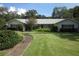 Charming single-story home with a lush lawn, mature trees, and a welcoming walkway leading to the front door at 2143 Wrens Way, Clearwater, FL 33764