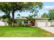 Charming home featuring a lush front yard, mature tree, palm trees, and a well-maintained lawn at 2560 51St N St, St Petersburg, FL 33710