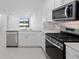 Open-concept kitchen with stainless steel appliances, white cabinets, and view of the pond and backyard at 27132 Capri Shores Cir, Englewood, FL 34223