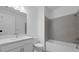 Bright bathroom with tub, sleek gray tile surround, vanity with modern hardware and updated fixtures at 27136 Capri Shores Cir, Englewood, FL 34223