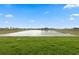 Scenic view of a large retention pond surrounded by lush green grass under a clear blue sky at 27136 Capri Shores Cir, Englewood, FL 34223