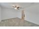 A spacious bedroom features neutral carpet, ceiling fan and a doorway to a bathroom at 3186 Oyster Cove St, Wimauma, FL 33598
