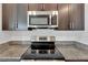 Kitchen appliances include a glass cooktop and stainless steel microwave and dark brown cabinets with granite countertops at 3186 Oyster Cove St, Wimauma, FL 33598
