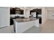 Modern kitchen with a large island, granite countertops, stainless steel appliances, and dark cabinetry at 3186 Oyster Cove St, Wimauma, FL 33598