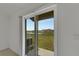 An open sliding glass door frames views of the expansive backyard and nearby pond at 3186 Oyster Cove St, Wimauma, FL 33598