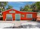 Bright orange community hall exterior with a blue door, bench and vibrant landscaping at 350 Kentucky Ave, Crystal Beach, FL 34681