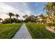 View of a well-manicured lawn and walkway leading to charming homes with lush tropical landscaping and palm trees at 350 Kentucky Ave, Crystal Beach, FL 34681