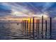 Picturesque waterfront view at sunset with calm waters and wooden posts creating a tranquil and inviting scene at 350 Kentucky Ave, Crystal Beach, FL 34681