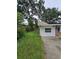 Exterior view featuring white siding, a paved driveway, and green shrubs at 3614 E Grove St, Tampa, FL 33610