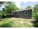 Exterior view showcasing the house's back wall with windows, a utility unit, and a grassy, partially sandy yard at 3632 E Comanche Ave, Tampa, FL 33610