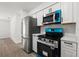 Modern kitchen featuring stainless steel appliances and stylish blue accents, with bright white cabinets and countertops at 3632 E Comanche Ave, Tampa, FL 33610