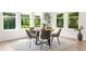 The sunlit dining area features a round wood table, modern chairs, and large windows overlooking lush greenery at 4383 Ortona Ln, Wesley Chapel, FL 33543