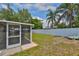 Backyard view featuring a screen lanai, well-maintained lawn, and privacy fence at 540 Firefly Ln, Apollo Beach, FL 33572