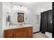 Bright bathroom features a wood vanity with cream countertop and round mirror at 5533 Golden Nugget Dr, Holiday, FL 34690