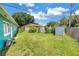 A grassy backyard with a turquoise house, storage shed, and partially fenced for privacy at 6195 28Th N Ave, St Petersburg, FL 33710