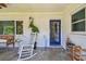 View of the covered front porch with blue front door and rocking chair at 859 Patterson Dr, Sarasota, FL 34234