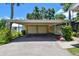 Two car garage with a carport, next to a home with manicured landscaping, a new driveway, and mature trees at 859 Patterson Dr, Sarasota, FL 34234