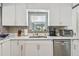 This kitchen features white cabinets, marble countertops and backsplash, stainless steel appliances, and a sink with a window at 859 Patterson Dr, Sarasota, FL 34234