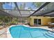 Sparkling in-ground pool with a screened enclosure, complemented by an outdoor dining area and a lush landscape at 859 Patterson Dr, Sarasota, FL 34234