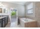 Bright bathroom featuring granite countertop, tile flooring, and a soaking tub with a view at 9860 Smarty Jones Dr, Ruskin, FL 33573
